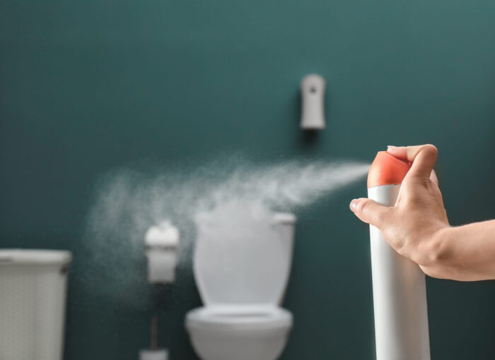 Woman spraying washroom product air freshener